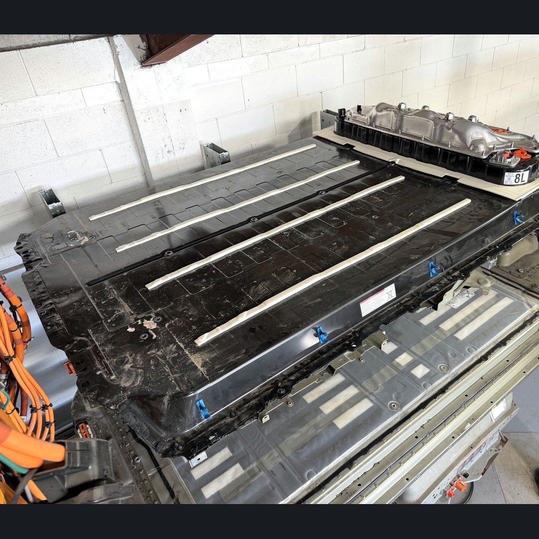 Tesla Model 3/Y LFP traction pack on the workshop floor in Taupō, top cover and HV junction box visible